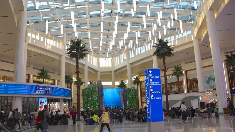 Bright, airy interior of Terminal C at Orlando International Airport with palm trees under a glass roof
