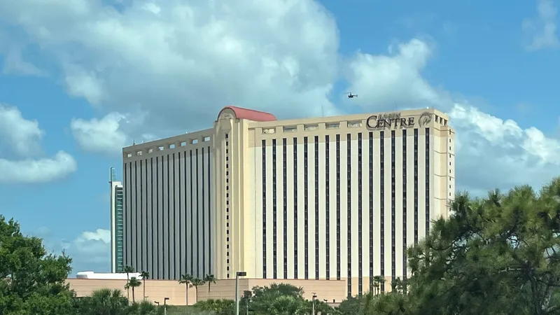 The tall cream-coloured Rosen Centre Hotel tower on International Drive, Orlando, under a blue sky with palm trees in front